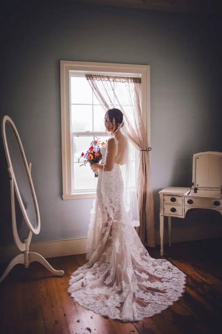 bride holding bouquet in front of window